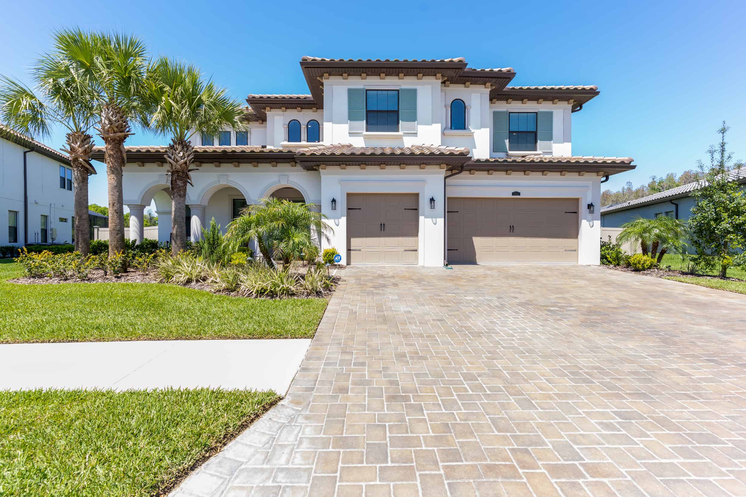 Lush tropical landscaping with palm trees complements a modern two-story house in Tampa, Florida.