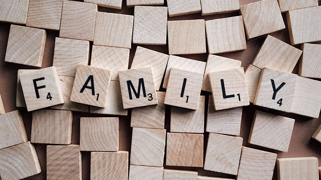 Family-themed wooden Scrabble tiles spelling "FAMILY" on a wooden surface.