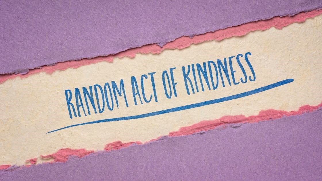 Random act of kindness written on torn paper with purple and pink background.