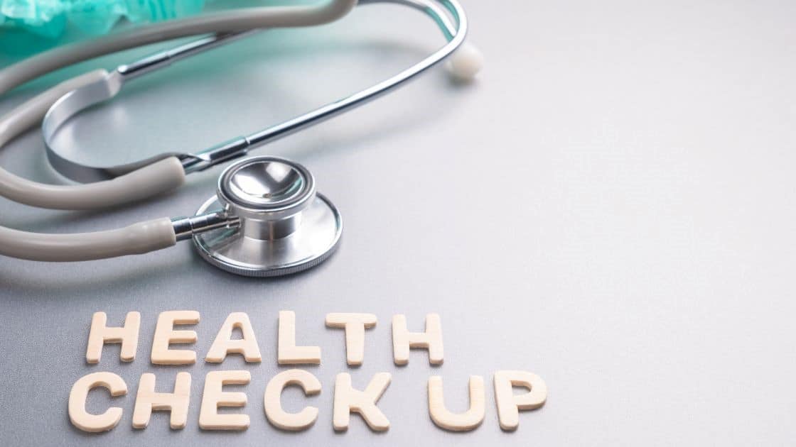 Stethoscope and "Health Check Up" wooden blocks on a table, healthcare, medical exam, wellness concept.