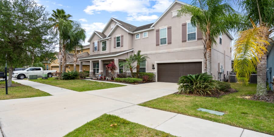 Spacious Tampa home exterior with lush landscaping and palm trees in a vibrant residential neighborhood.