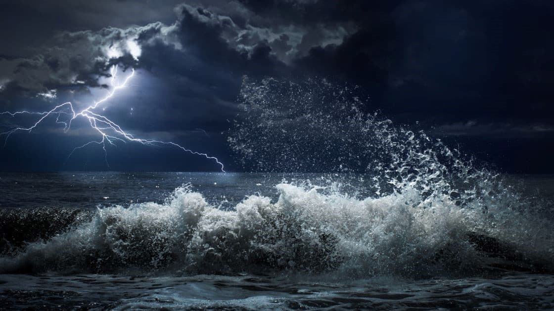 Lightning storm over turbulent ocean waves during a thunderstorm.