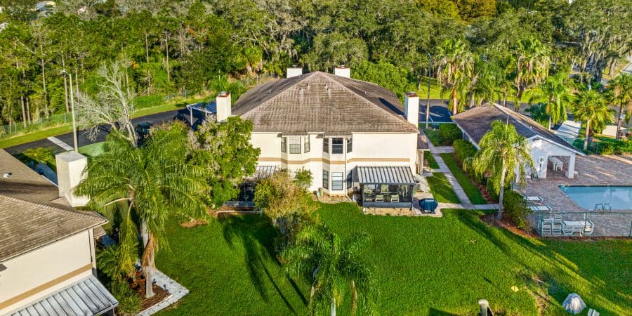 Spacious suburban home with a lush backyard, swimming pool, and palm trees in Tampa, Florida.