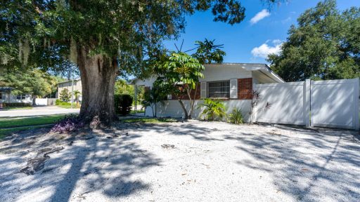 Lush front yard of a charming Florida home with mature trees and tropical landscaping.