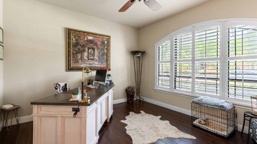 Modern home office with large window shutters, dark hardwood floors, and stylish decor.