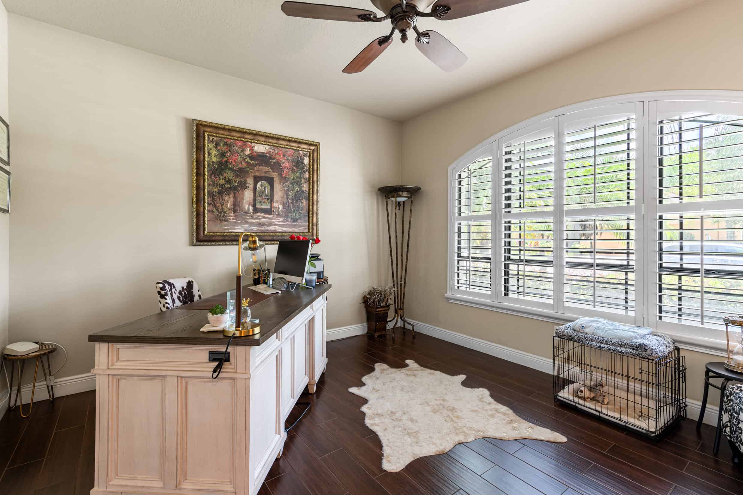 Modern home office with large window shutters, dark hardwood floors, and stylish decor.