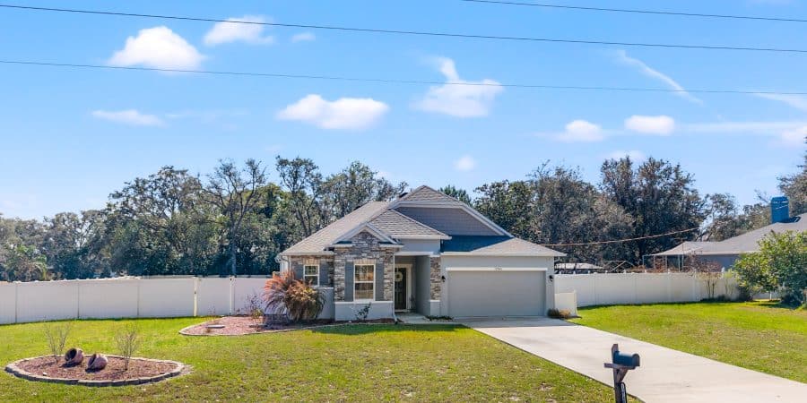Spacious suburban house with landscaped yard and white privacy fence in Tampa, Florida.