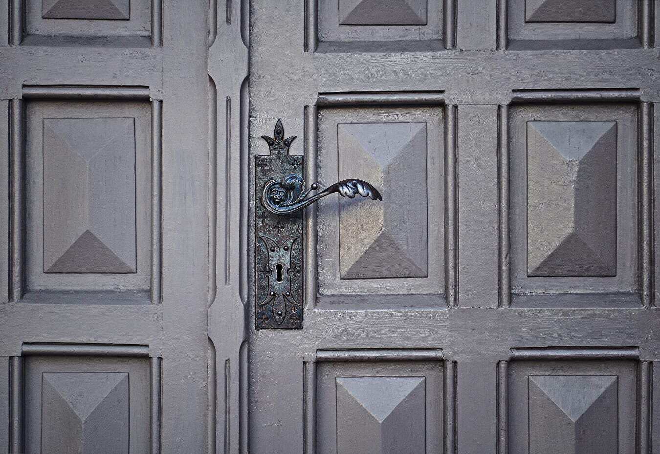 Beautifully crafted vintage iron door handle on a classic wooden garage door.